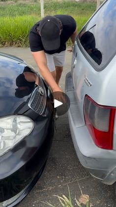 a man is waxing the hood of a black car with a brush and wrench