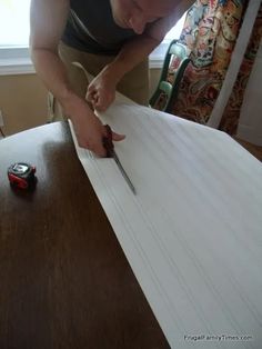 a man cutting paper with a pair of scissors on top of the table in front of him