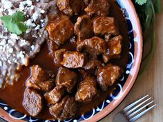 a plate filled with meat and gravy on top of a blue and white plate