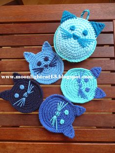 four crocheted cats sitting on top of a wooden bench