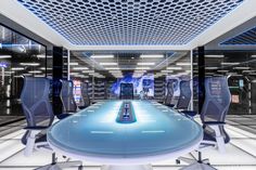 a futuristic office with blue and white chairs around a table in the middle of it