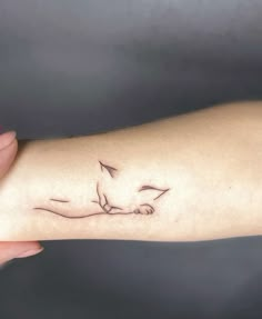 a woman's arm with a small bird tattoo on the left side of her arm