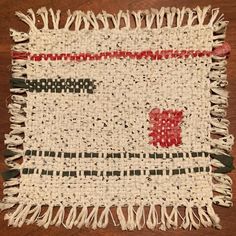 a piece of cloth with red, white and green designs on it sitting on a wooden table