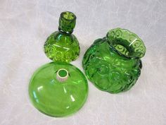 three green glass vases sitting next to each other on a white tableclothed surface