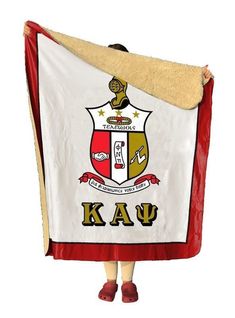 a person is holding up a coat with the letters kau on it and shield