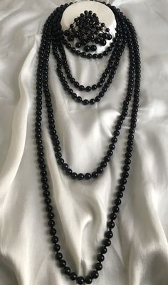 Vintage extremely stylish black Czech glass jewelry. Set of two long necklaces and a brooch, made in the 50s. Multi-strand beaded necklaces were immensely popular in 1950s. Heavy glass necklaces made of Czech shiny black beads in decadent Sautoir or Rope style. Made in the best tradition, each bead is knotted. Many uses for this jewelry. The length of the beads with lock is 65cm (130cm). Length of beads without lock 91cm (183cm). Diameter of glass beads 7-8 mm. Brooch size 27/60mm, heavy and tin Elegant Round Jewelry With 108 Beads, Classic Necklaces With Round Beads For Evening, Classic Beaded Evening Jewelry, Classic Beaded Jewelry For Evening, Single Strand Necklace With Round Beads For Evening, Evening Single Strand Necklace With Round Beads, Elegant Multi-strand Beaded Necklaces For Formal Occasions, Black Multi-strand Necklaces For Formal Occasions, Formal Black Multi-strand Jewelry