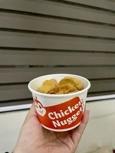 a person holding up a cup of chicken nuggets