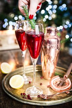 two glasses of red wine on a tray with silverware and a christmas tree in the background