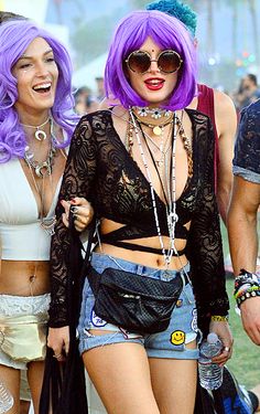 two women with purple hair are walking in front of the crowd at an outdoor music festival