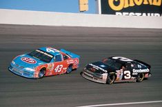 two cars racing on a race track during the day