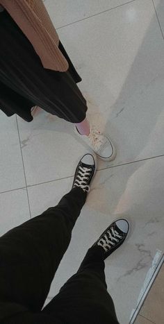 a person standing on the floor with their feet up and wearing black pants, white sneakers