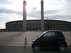 a smart car parked in front of the olympic rings