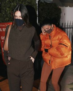 two women wearing masks walking down the street