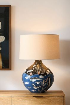 a blue and white vase sitting on top of a wooden dresser next to a lamp