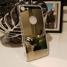 an iphone case sitting on top of a table next to a vase and framed photograph