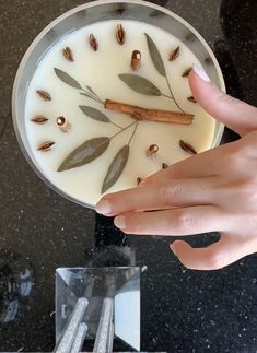 a person's hand reaching for something on a plate with leaves and cinnamon sticks