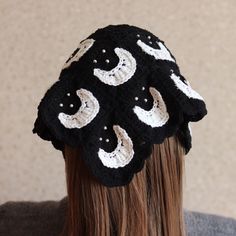 a woman wearing a black and white crocheted hat with crescents on it