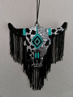 a cow skull with turquoise and black accents hanging from a wall ornament in a room