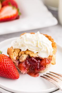 a strawberry pie on a plate with whipped cream and strawberries next to the slice