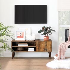 a living room with white walls and wooden furniture in front of a flat screen tv