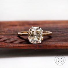 an oval cut diamond sits on top of a wooden surface, with the center stone visible