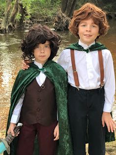 two young boys dressed up in costume standing next to each other on the side of a river