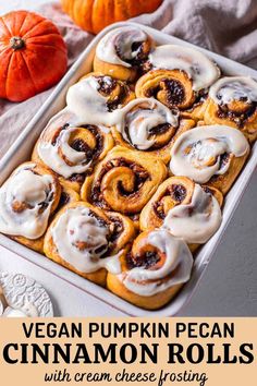 a pan filled with cinnamon buns on top of a table next to pumpkins