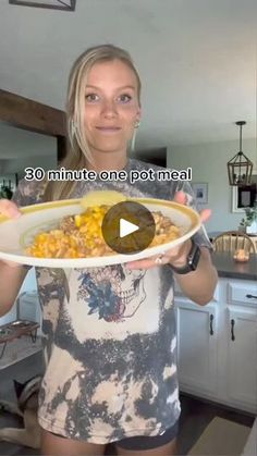 a woman holding a plate with corn on it