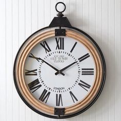 a clock hanging from the side of a wall with roman numerals on it