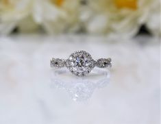 a diamond ring sitting on top of a table next to white flowers and roses in the background