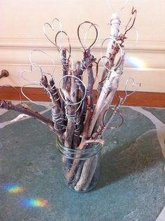 a glass vase filled with branches and wire on top of a green tablecloth covered floor