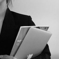 a woman holding an apple laptop computer in her hands and looking at the camera, black and white photo