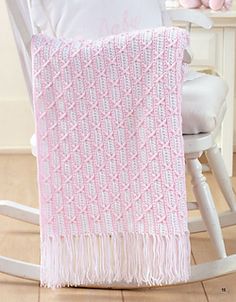 a pink knitted blanket sitting on top of a rocking chair