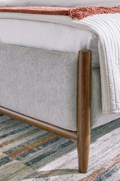 a close up of a bed with a wooden frame and foot board on top of it