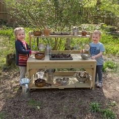 two young children standing in front of a table with pots and pans on it