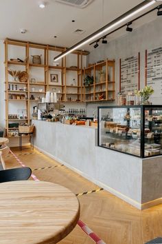 the inside of a restaurant with tables, chairs and shelves full of food on display