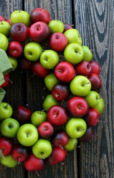 an apple wreath on a wooden surface with green and red apples in the shape of a letter o