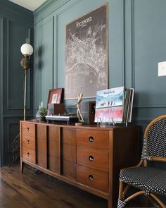 a wooden dresser sitting next to a chair in a room with green paint on the walls