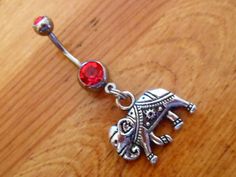 an elephant belly ring with a red stone in the center on a wooden table top