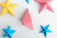 four origami stars are arranged on a white surface, one is pink and one is blue