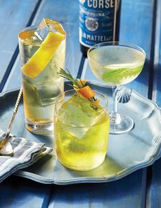 two glasses filled with lemonade and garnished with an orange slice on a tray