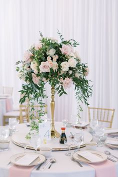 the centerpieces on this table are filled with pink and white flowers, greenery, and silverware