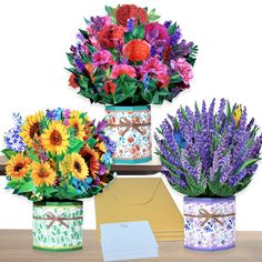 three vases filled with colorful flowers sitting on top of a table next to an envelope