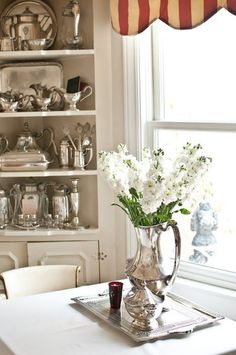 a vase with white flowers sitting on top of a table in front of a window