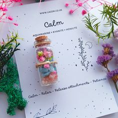 a jar filled with flowers sitting on top of a white paper next to pink and purple flowers