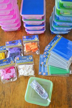 many different colored legos in plastic containers on a wooden table next to each other