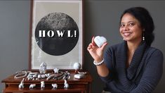 a woman sitting in front of a table with jewelry on it and the words how