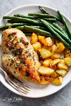 chicken, potatoes and green beans on a white plate with a fork next to it