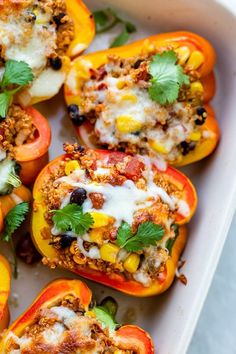 stuffed bell peppers in a white casserole dish topped with cheese and cilantro