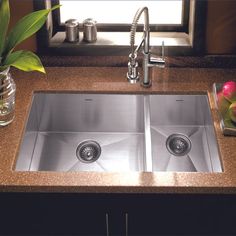 two stainless steel sinks in a granite countertop with flowers and vases on the side